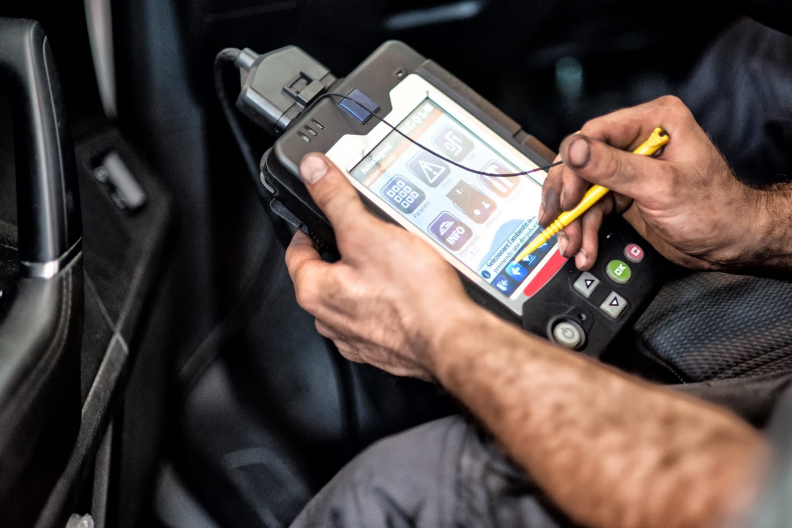 Técnico utiliza um scanner de diagnóstico portátil dentro da cabine de um veículo.